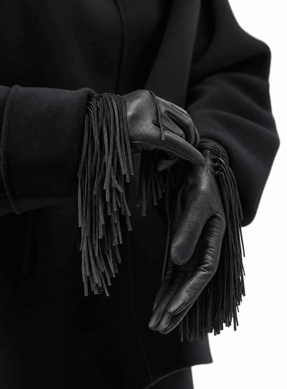 hands in black nappa leather gloves with a deep black fringe at the wrist, against a black wool coat