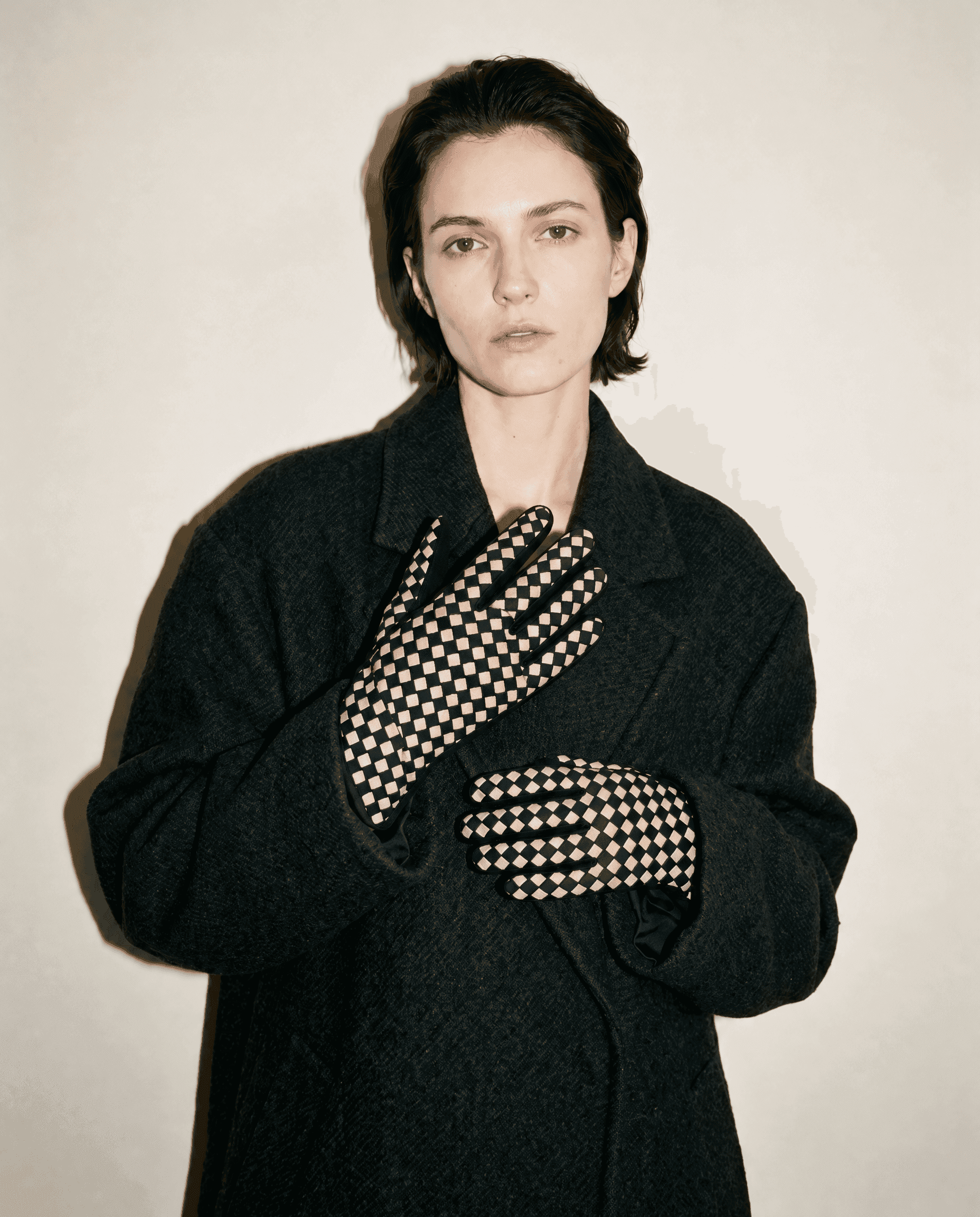black suede gloves with a cream checkerboard across the back of the hand, worn with an oversized charcoal wool coat