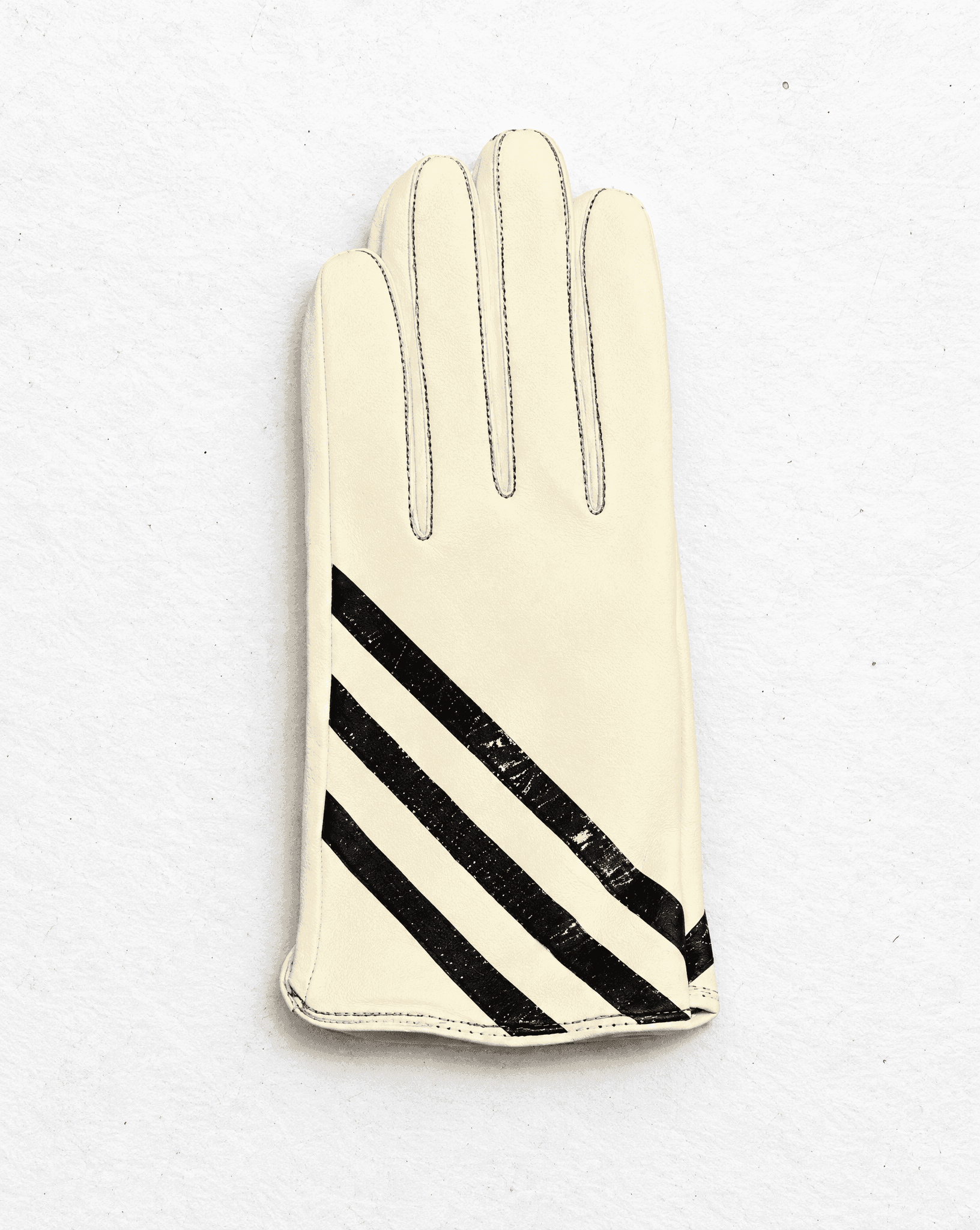 a single cream nappa leather glove with three glossy black diagonal stripes and dark stitching along the fingers