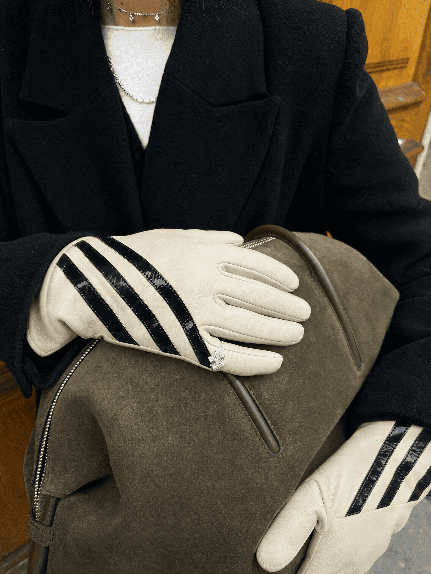 a ring worn over cream nappa leather gloves with three glossy black stripes